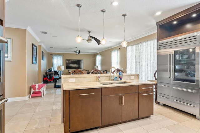 kitchen featuring a center island with sink, sink, ceiling fan, ornamental molding, and light tile patterned flooring