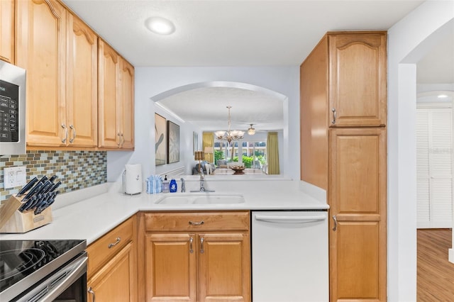 kitchen featuring tasteful backsplash, white dishwasher, light wood-type flooring, an inviting chandelier, and sink