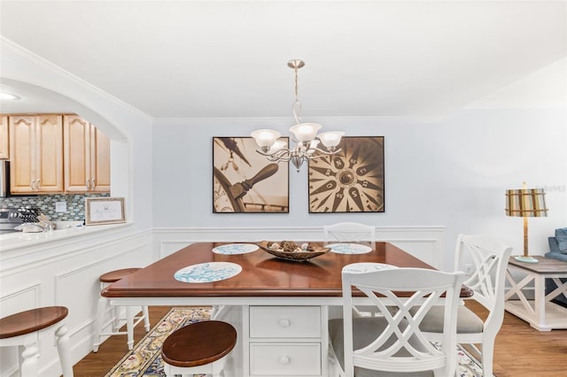 dining area featuring ornamental molding, a chandelier, and hardwood / wood-style flooring