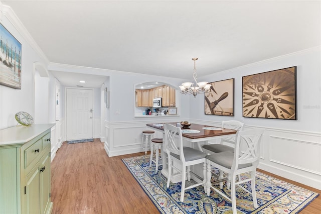 dining space featuring ornamental molding, a chandelier, and light hardwood / wood-style floors