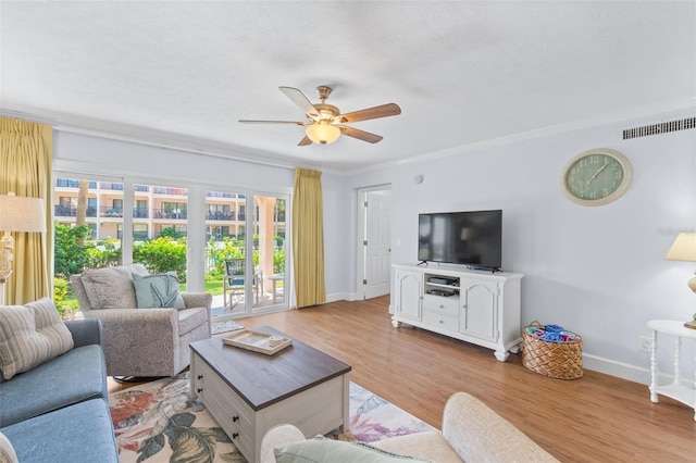 living room with light wood-type flooring, crown molding, and ceiling fan