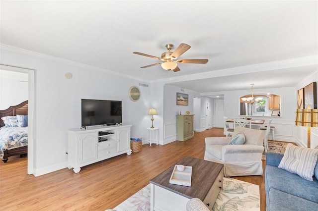 living room featuring ceiling fan with notable chandelier, light hardwood / wood-style floors, and crown molding