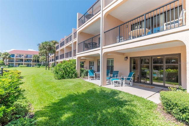 back of house with a balcony, a lawn, and a patio area