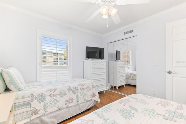 bedroom featuring a closet, ceiling fan, wood-type flooring, and crown molding