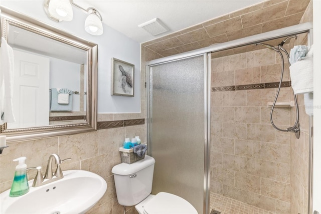 bathroom featuring tile walls, sink, an enclosed shower, and toilet