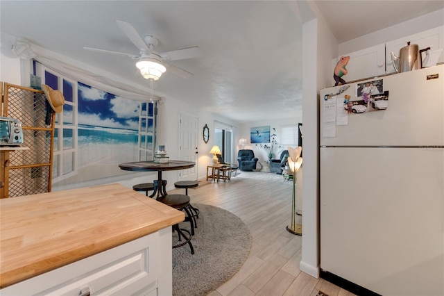 dining area with light hardwood / wood-style floors and ceiling fan