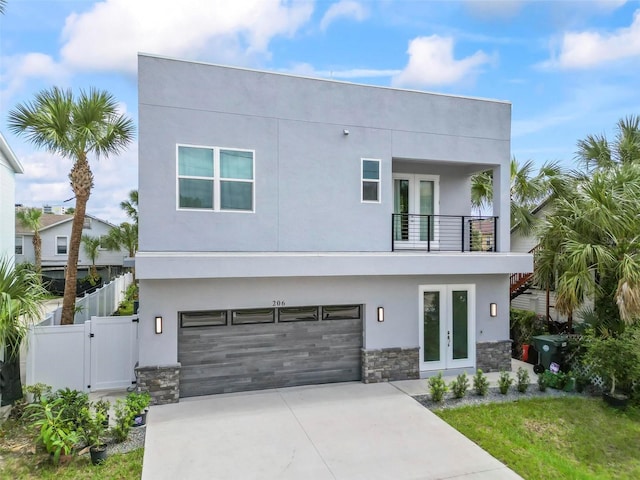 contemporary house with a balcony, a garage, and french doors