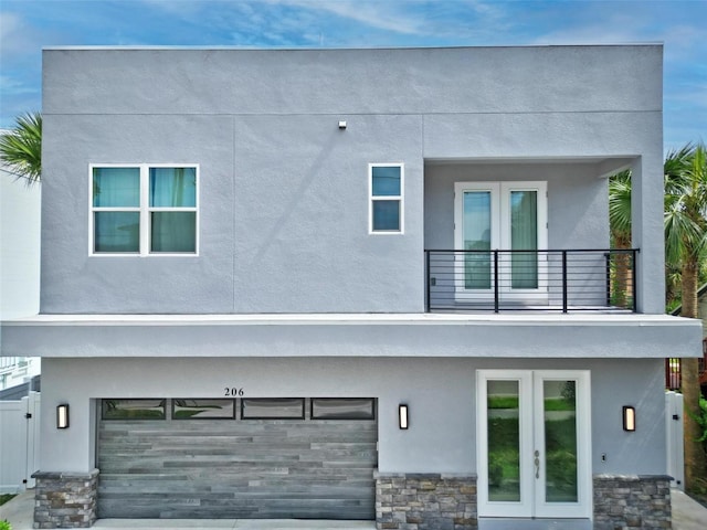 rear view of house featuring a balcony, french doors, and a garage