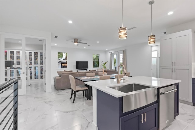 kitchen featuring ceiling fan, sink, decorative light fixtures, a kitchen island with sink, and dishwasher