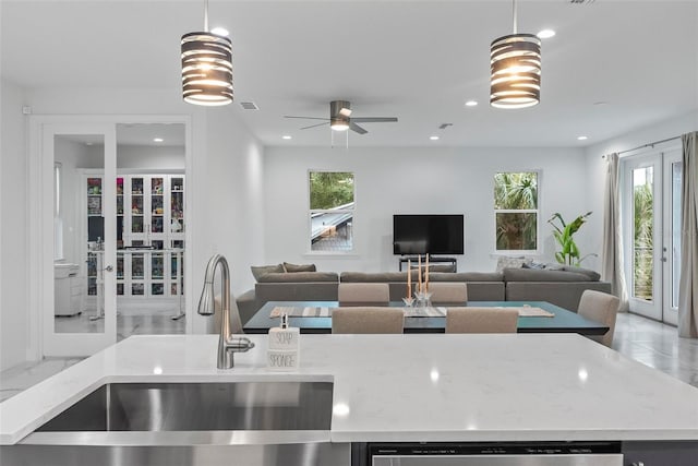 kitchen with light stone counters, light tile patterned floors, decorative light fixtures, and sink