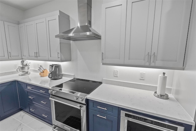 kitchen featuring blue cabinets, white cabinets, beverage cooler, wall chimney exhaust hood, and high end stove