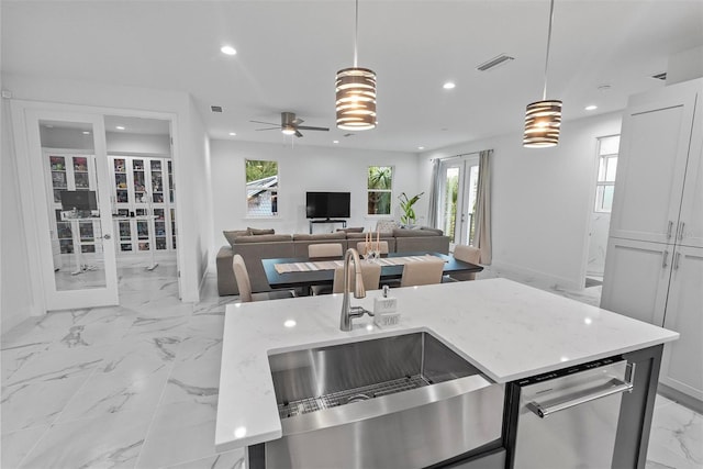 kitchen with ceiling fan, pendant lighting, light stone countertops, and white cabinetry