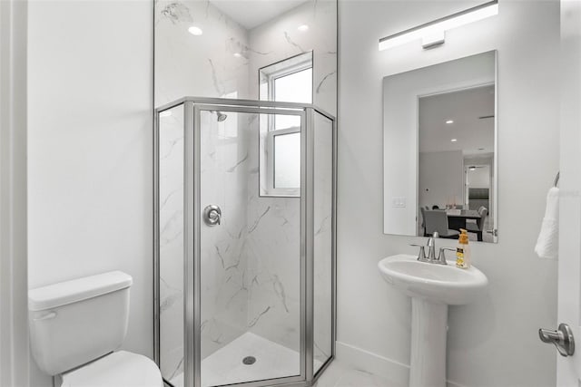 bathroom with plenty of natural light, a shower with shower door, and toilet