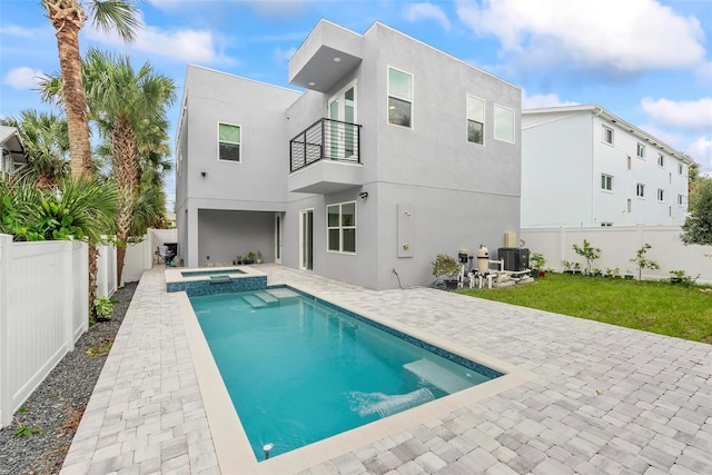 rear view of property with a balcony, a patio, a swimming pool with hot tub, and central air condition unit