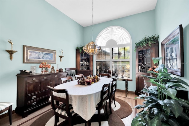 dining space featuring light wood-type flooring, a chandelier, and high vaulted ceiling