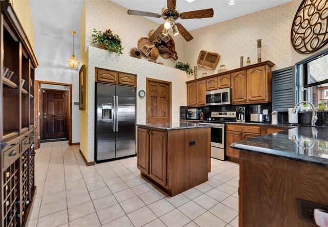 kitchen featuring ceiling fan, sink, decorative light fixtures, stainless steel appliances, and a center island