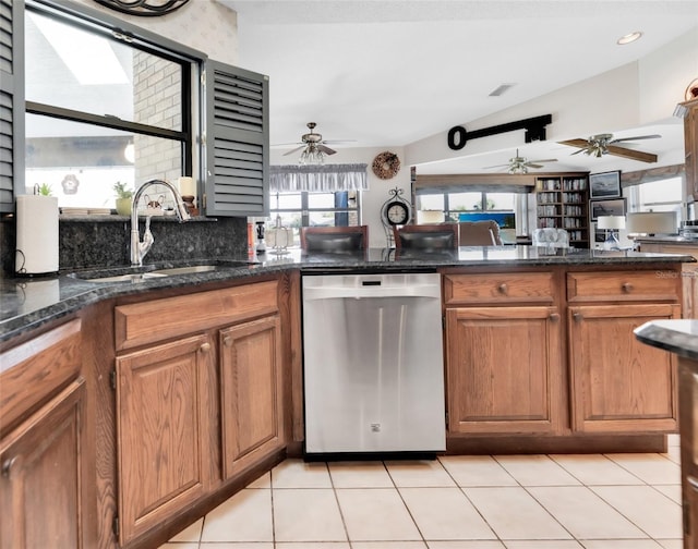 kitchen with dark stone counters, dishwasher, light tile patterned floors, and sink