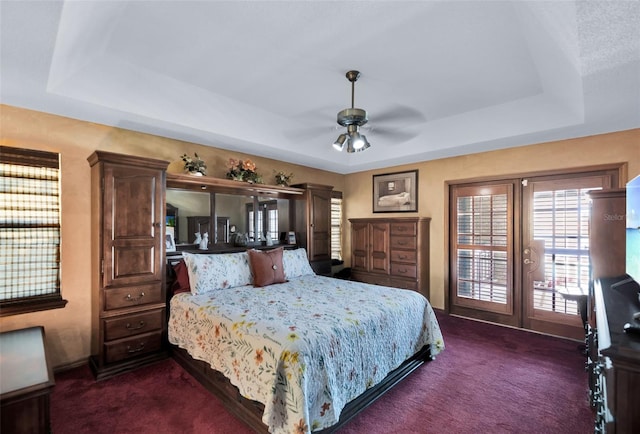 carpeted bedroom with a tray ceiling and ceiling fan