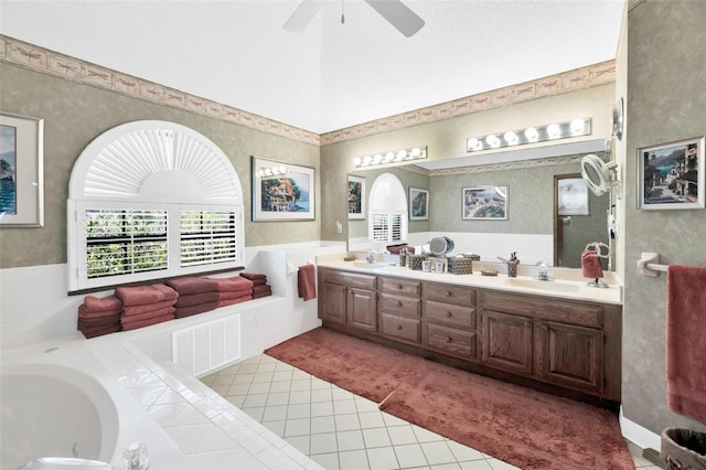 bathroom featuring ceiling fan, vanity, a relaxing tiled tub, a textured ceiling, and tile patterned flooring