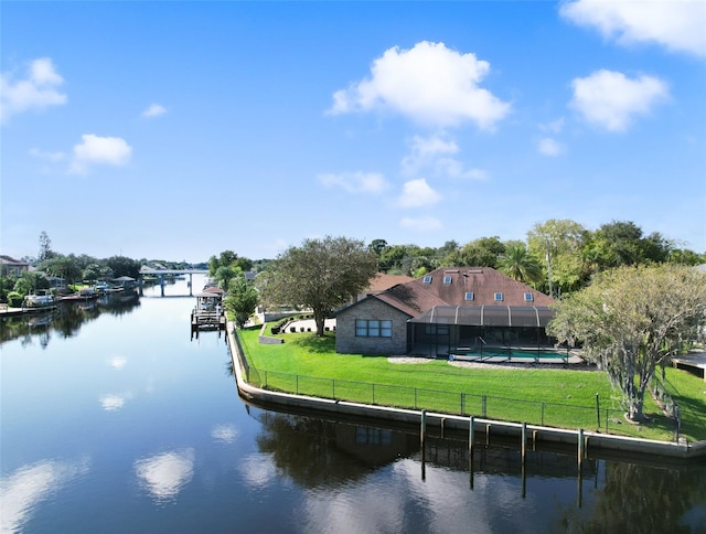 dock area with glass enclosure, a water view, and a lawn