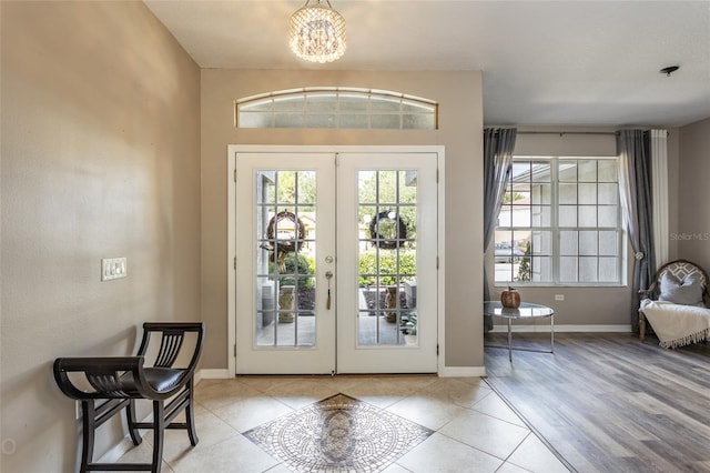 doorway with tile patterned floors, french doors, baseboards, and an inviting chandelier