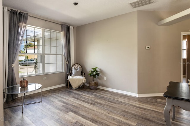 living area with wood finished floors, visible vents, and baseboards