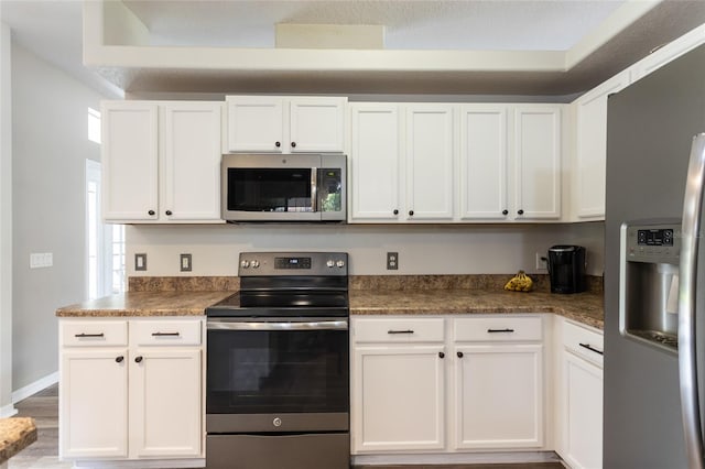 kitchen with white cabinets, a textured ceiling, stainless steel appliances, and hardwood / wood-style floors