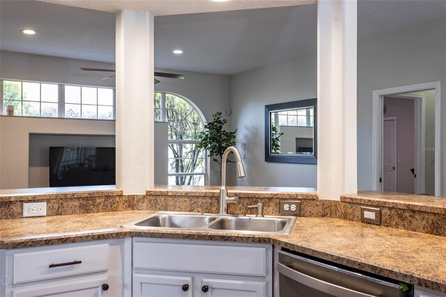 kitchen with stainless steel dishwasher, sink, ceiling fan, and white cabinets