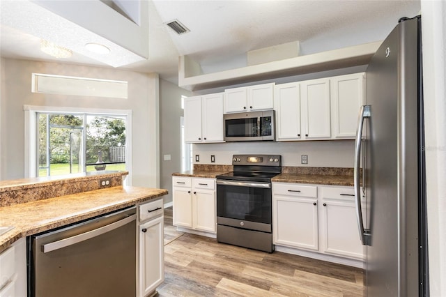 kitchen with white cabinets, stainless steel appliances, visible vents, and light wood finished floors