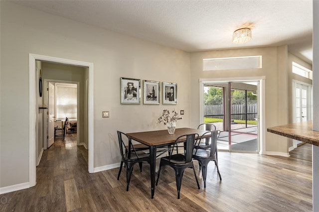 dining room with a textured ceiling and dark hardwood / wood-style floors