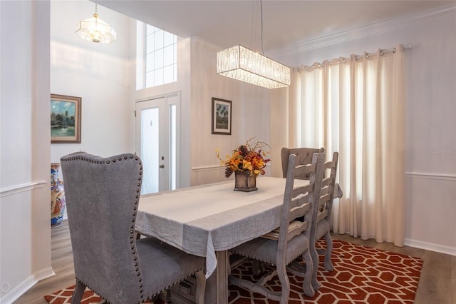 dining area with crown molding, a notable chandelier, and hardwood / wood-style flooring