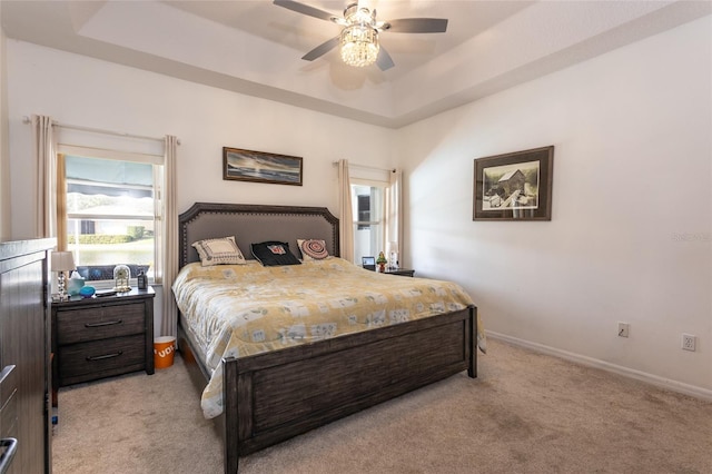 carpeted bedroom with a tray ceiling and ceiling fan