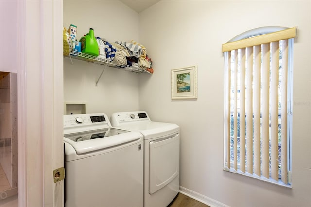 laundry room featuring dark wood-type flooring, a healthy amount of sunlight, and washing machine and clothes dryer