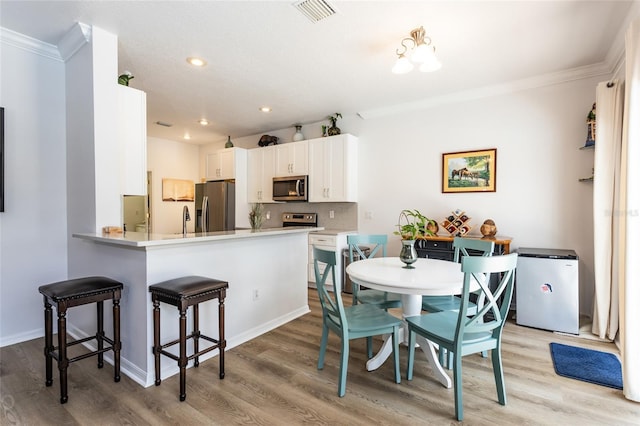 dining room featuring crown molding and light hardwood / wood-style flooring