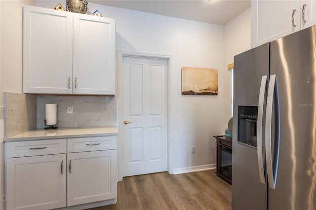 kitchen featuring decorative backsplash, light hardwood / wood-style flooring, stainless steel refrigerator with ice dispenser, white cabinetry, and light stone counters