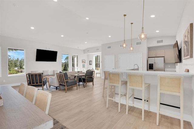 kitchen featuring stainless steel fridge, light wood-type flooring, pendant lighting, and a healthy amount of sunlight