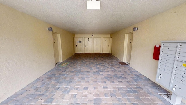 hall with a textured ceiling and a mail area