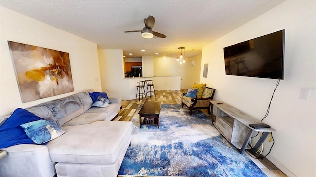 living room with ceiling fan with notable chandelier and hardwood / wood-style floors