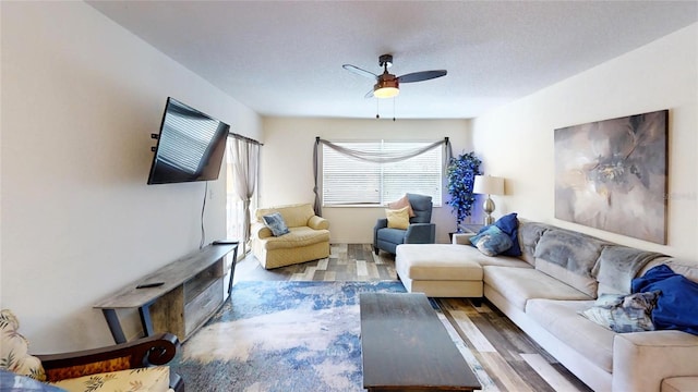 living room featuring wood-type flooring, ceiling fan, and a textured ceiling