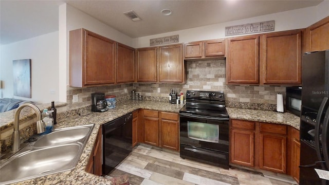 kitchen with light stone counters, sink, decorative backsplash, and black appliances