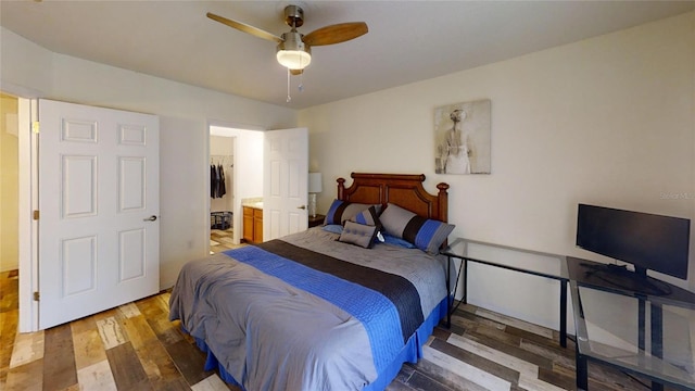 bedroom with ceiling fan, dark wood-type flooring, a closet, a spacious closet, and ensuite bath