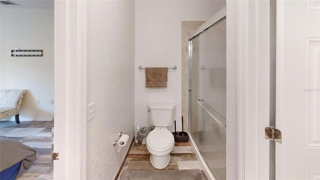 bathroom with a shower with shower door and toilet