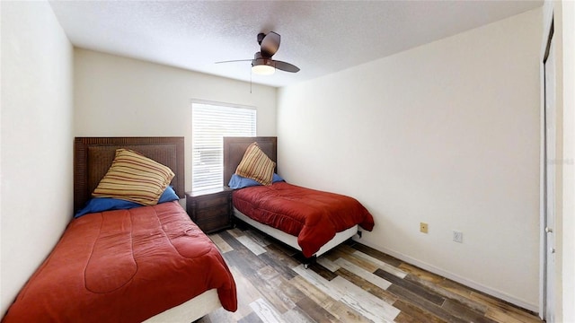 bedroom with ceiling fan, dark hardwood / wood-style floors, and a textured ceiling