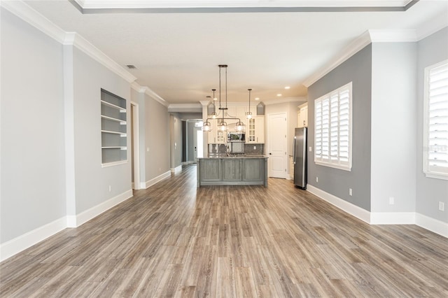 kitchen with hardwood / wood-style floors, hanging light fixtures, a center island with sink, and appliances with stainless steel finishes