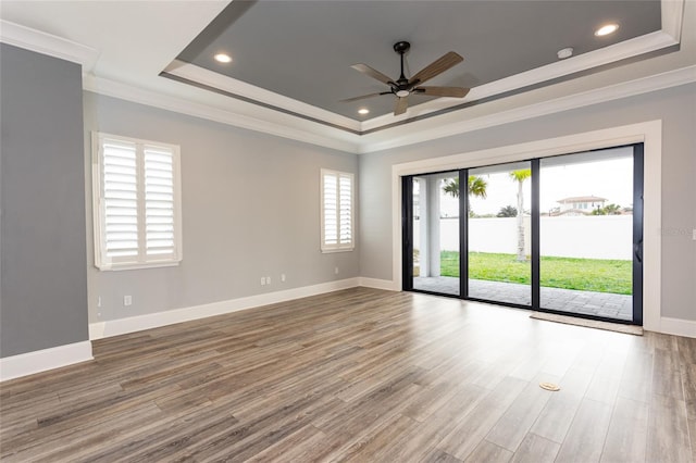 unfurnished room featuring ornamental molding, hardwood / wood-style flooring, ceiling fan, and a tray ceiling