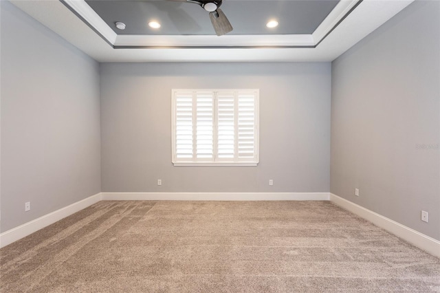 carpeted empty room with a tray ceiling and ceiling fan