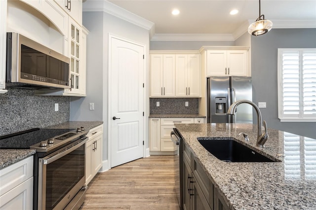 kitchen featuring appliances with stainless steel finishes, light stone counters, sink, white cabinetry, and hanging light fixtures