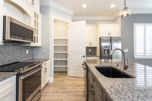 kitchen featuring sink, hanging light fixtures, light stone counters, white cabinetry, and stainless steel appliances