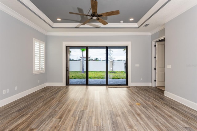 unfurnished room featuring ceiling fan, wood-type flooring, ornamental molding, and a tray ceiling