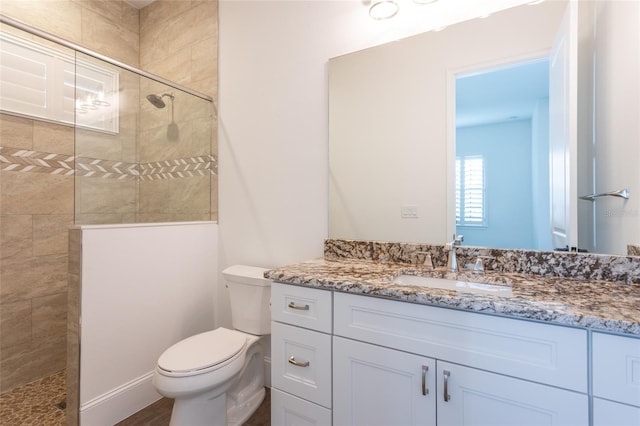 bathroom featuring tiled shower, vanity, and toilet